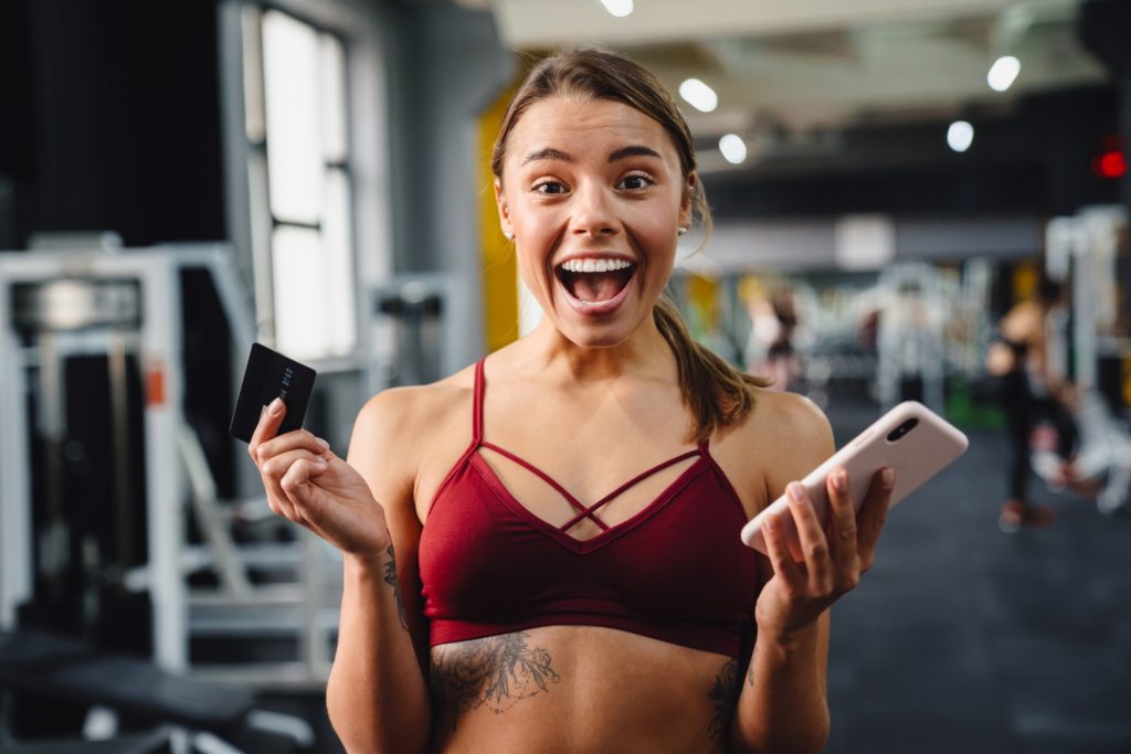 Excited young woman fitness coach using mobile phone