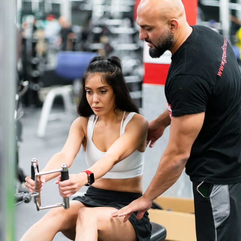 Personal trainer guiding woman on how to use gym equipment at GROW Fitness, a gym in Etobicoke